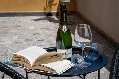 a bottle of wine on a table with a book and a glass at Art e Dimora - Boutique Room. in Castellammare del Golfo