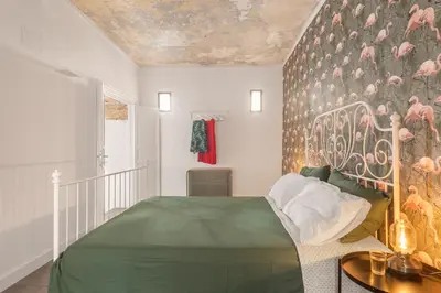 a bedroom with a green bed and a wall with pink birds at 124 Maqueda Apartments in Palermo