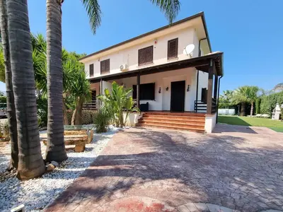 a house with palm trees in front of it at Villa Jari in Carini