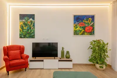 a living room with a tv and a chair and paintings at Casa Imperia in Palermo