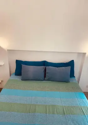 a bed with blue and green pillows on it at Casa Lella Holiday Boutique in Palermo