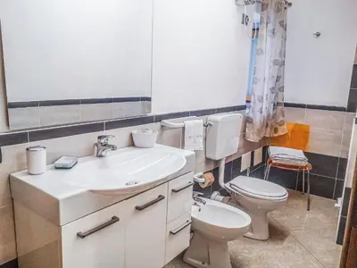 a bathroom with a sink and a toilet and a mirror at Casaulente in Alcamo
