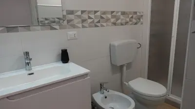 a white bathroom with a toilet and a sink at Stella di Mare in Balestrate