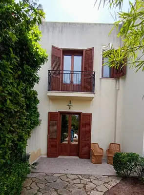 a white building with a red door and windows at Casa VISTA MARE in Macari