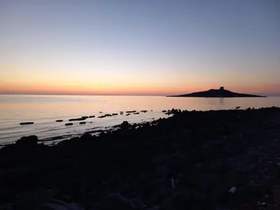 a sunset over the water with a group of rocks at La Coccinella 