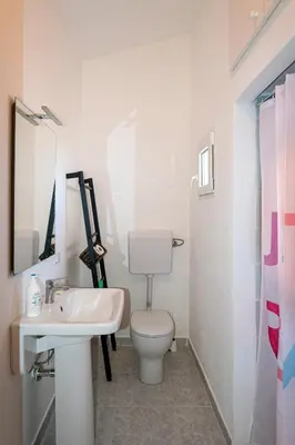 a white bathroom with a toilet and a sink at Villa Piano Vignazza in Scopello