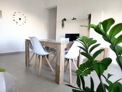 a wooden table with white chairs in a room at Dove il mare incontra il Relax!Ampio appartamento Conchiglia Home in Alcamo Marina