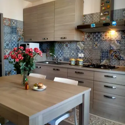 a kitchen with a table with a vase of red roses at Casa vacanza Luisa in Alcamo Marina