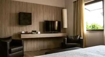 a hotel room with a bed and two chairs and a television at Hotel Federico II Central Palace in Palermo
