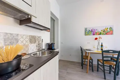 a kitchen with a sink and a table with chairs at CoralBay San Vito lo Capo - Appartamento in San Vito lo Capo