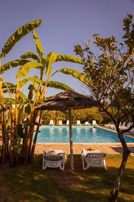 two tables and a umbrella next to a swimming pool at Agriturismo Villa Cefalà in Santa Flavia