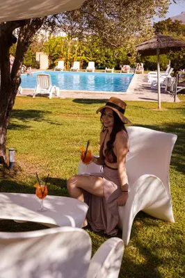a woman sitting on a chair with a drink at Agriturismo Villa Cefalà in Santa Flavia