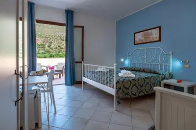 a bedroom with a bed and a table and a window at Hotel Achibea in San Vito lo Capo
