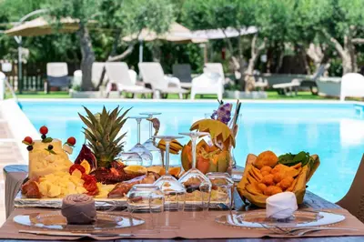 a tray of food on a table next to a pool at Hotel Achibea in San Vito lo Capo