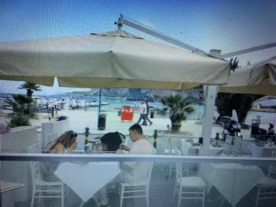 a group of people sitting at a table under an umbrella at Casa Enza Partanna Mondello in Palermo