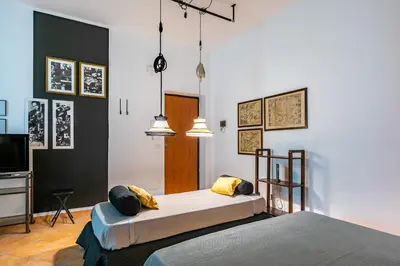 a bedroom with two beds and a tv and pendant lights at GuestHost - Ballarò Central Cozy Studio with Balcony in Palermo
