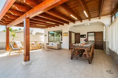 an outdoor patio with a wooden ceiling and a table at Villa DellOmbra in Alcamo