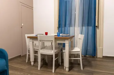 a dining room table with white chairs and a blue curtain at Vittorio Emanuele Charming Central Flats in Palermo