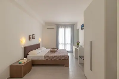 a bedroom with a bed and a room with a window at Hotel Sikania in San Vito lo Capo