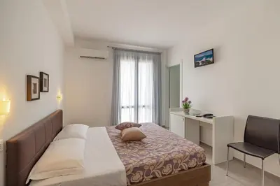 a bedroom with a bed and a desk and a chair at Hotel Sikania in San Vito lo Capo