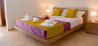 a bedroom with a large bed with towels on it at Hotel Sikania in San Vito lo Capo