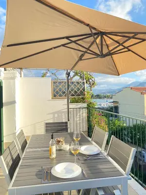 a wooden table with an umbrella on a balcony at The White Sail - Mondello Apartment with Terrace - casa di vincenzo e andrea in Mondello