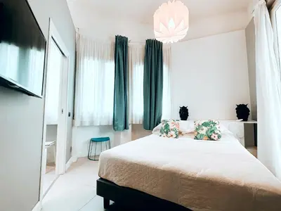 a bedroom with a bed with green curtains and a tv at Villa Calipso in Mondello
