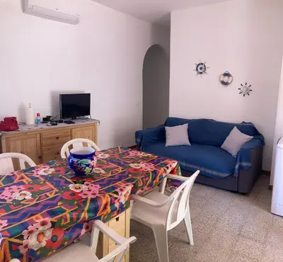 a living room with a table and a blue couch at Like Home Calamazzo di Sciacca in Scopello