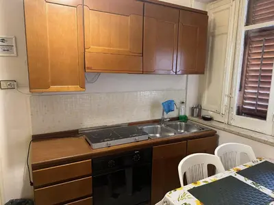 a kitchen with wooden cabinets and a sink and a table at Apartament Dimora di Maury a due passi dai trasporti e da Ballarò in Palermo