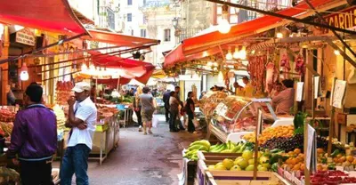 a group of people walking around a market with fruits and vegetables at Apartament Dimora di Maury a due passi dai trasporti e da Ballarò in Palermo