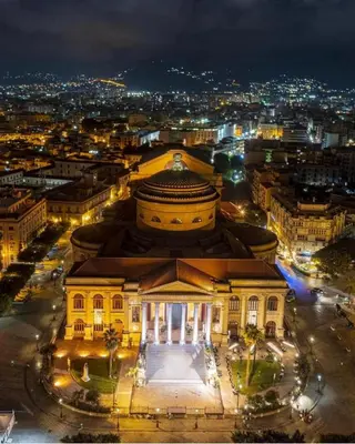 a building at night with a city in the background at Hola Cathedral House Porta di Castro in Palermo