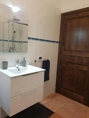 a bathroom with a white sink and a wooden door at Villa delle Pomelie - Castellammare del Golfo in Alcamo