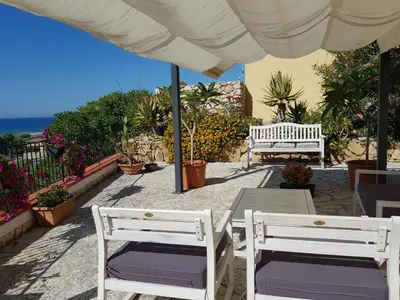 two white chairs and a table under an umbrella at Villa delle Pomelie - Castellammare del Golfo in Alcamo