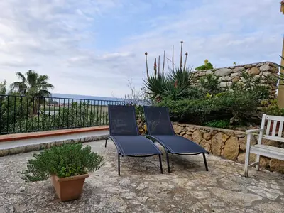 two chairs sitting on a patio overlooking the ocean at Villa delle Pomelie - Castellammare del Golfo in Alcamo