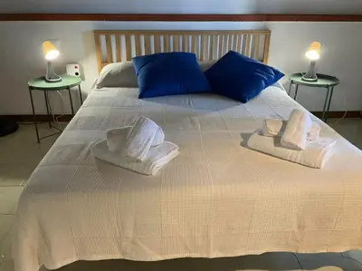 a large white bed with blue pillows and towels on it at la Casetta di Laura in Terrasini