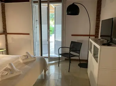 a bedroom with a bed and a tv and a chair at la Casetta di Laura in Terrasini