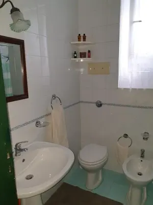 a white bathroom with a sink and a toilet at Casa Delizia in Lido di Mondello