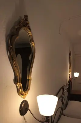 a gold mirror on a wall next to a lamp at La Giara in Palermo