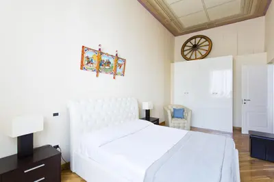 a bedroom with a white bed and a clock on the wall at Quattro canti luxury apartment in Palermo