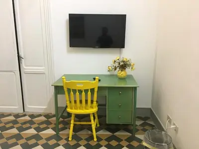 a green desk with a yellow chair and a television on a wall at Le stanze di Regina Margherita in Palermo