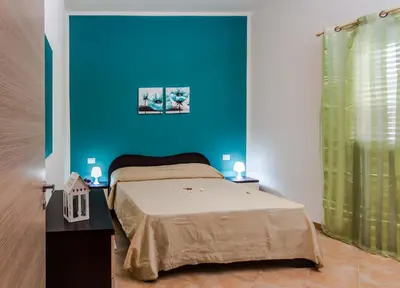 a bedroom with a bed and a blue wall at Casa vacanze Biondo in Trappeto