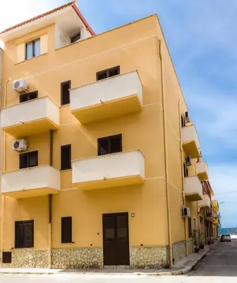 a yellow building with balconies on a street at Casa vacanze Biondo in Trappeto