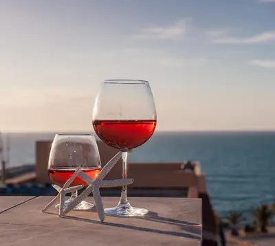 two glasses of wine sitting on a table near the ocean at Casa vacanze Biondo in Trappeto