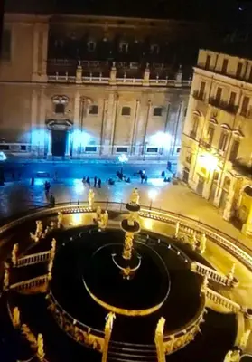 a view of a building with a fountain at night at Hola House al Capo in Palermo