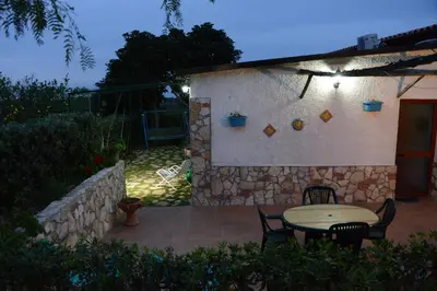 a patio with a table and chairs and a stone wall at Holiday Homes in Campofelice di Roccella