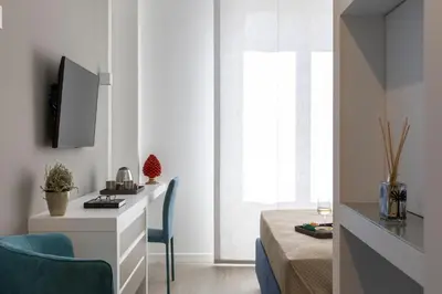 a room with a bed and a desk with a tv at La Musa Apartments & Rooms in Palermo