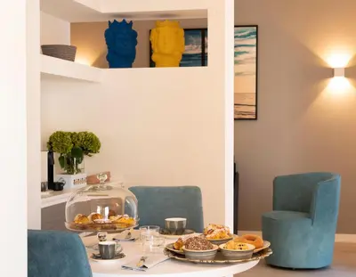 a table with plates of food and blue chairs at La Musa Apartments & Rooms in Palermo