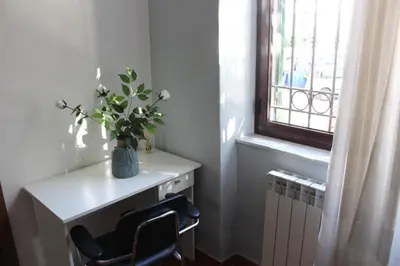 a room with a desk and a vase of flowers on a window at Himera Holiday in Palermo