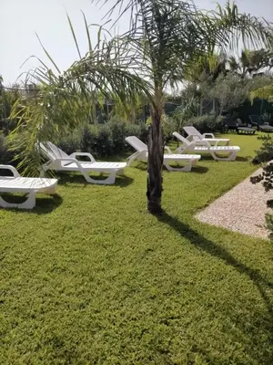 a row of white benches in a park with a palm tree at Garden Voyages Balestrate in Balestrate