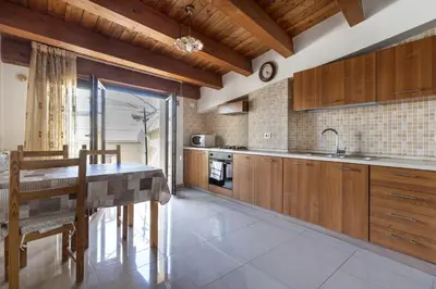 a kitchen with wooden cabinets and a dining table at Ideal Residence & SPA in Alcamo